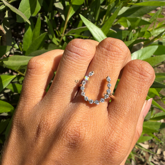Open U-shaped diamond horseshoe knuckle ring worn on hand in natural outdoor daylight