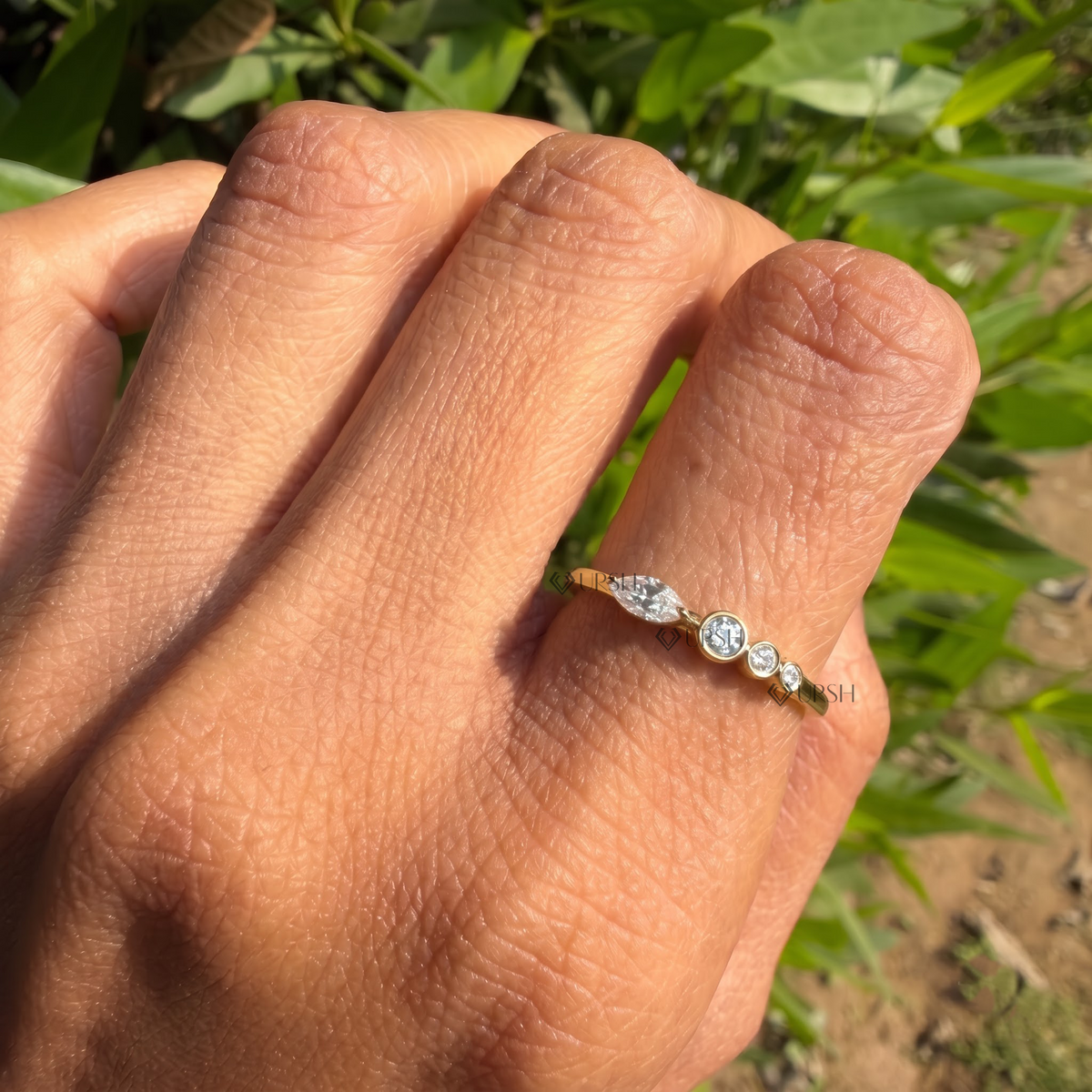 Bezel-set marquise and round diamond multi-stone ring styled gracefully on finger in natural daylight