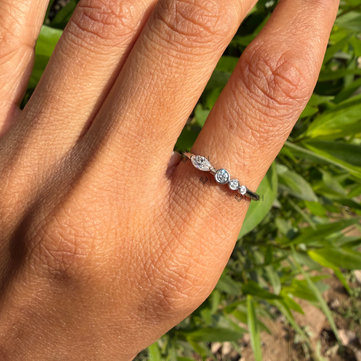 Daylight angle view of multi-stone bezel-set diamond ring worn on hand showcasing modern asymmetric styling