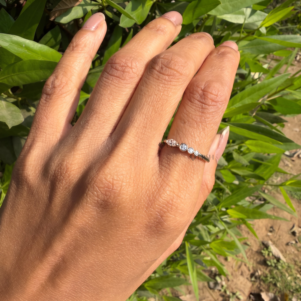 Detailed daylight macro close-up of bezel-set marquise and graduating round lab diamonds held on finger