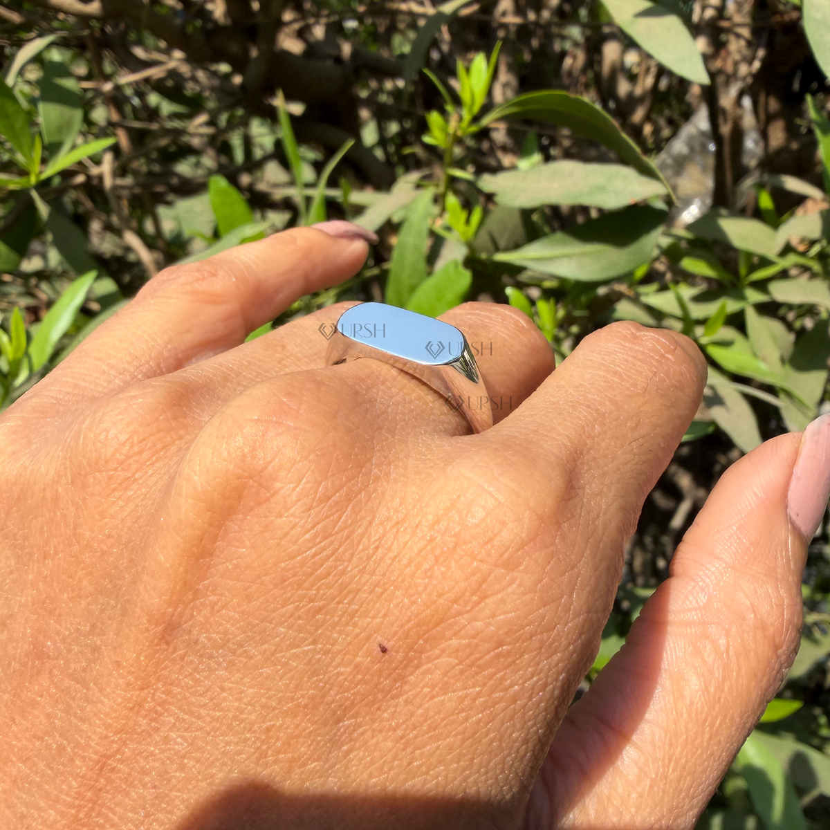 Daylight angle view of white gold minimalist signet ring worn on hand