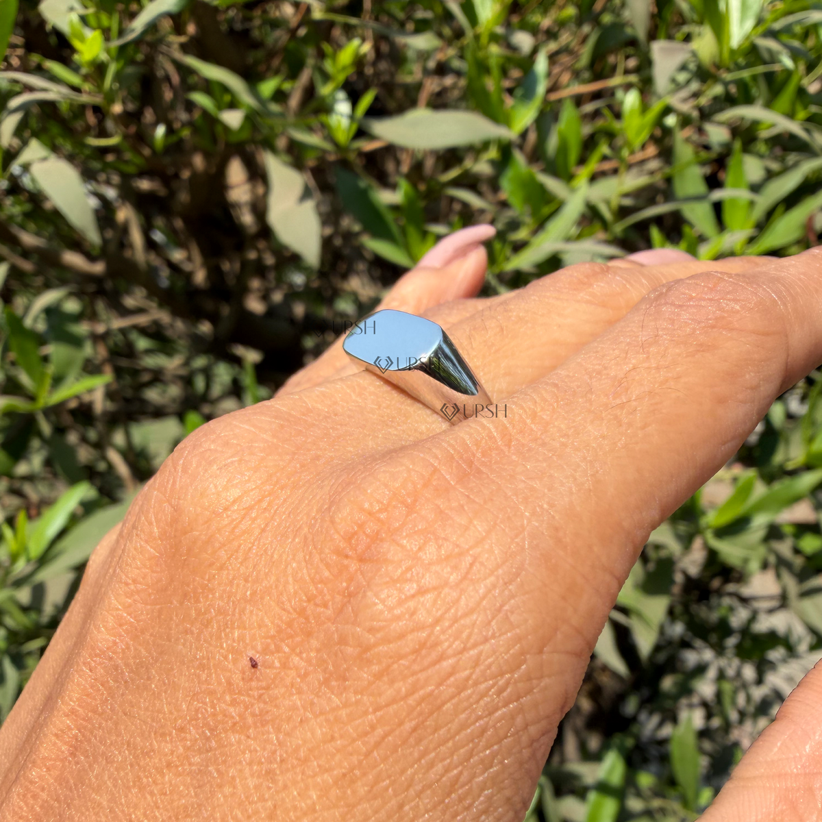 Close-up daylight angle view of white gold signet ring worn on finger