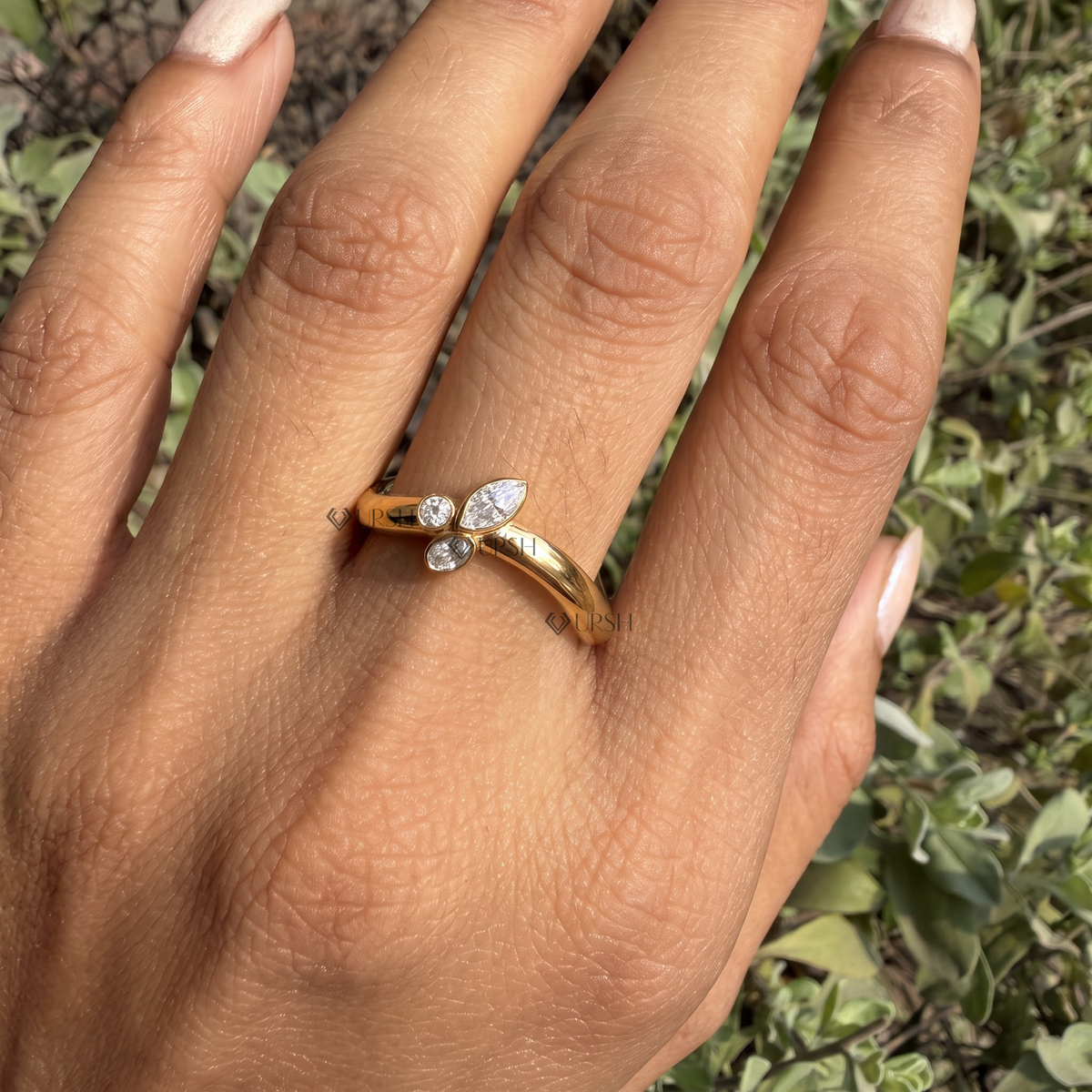 Bezel-set round, marquise, and pear diamond curved ring styled gracefully on finger in natural daylight