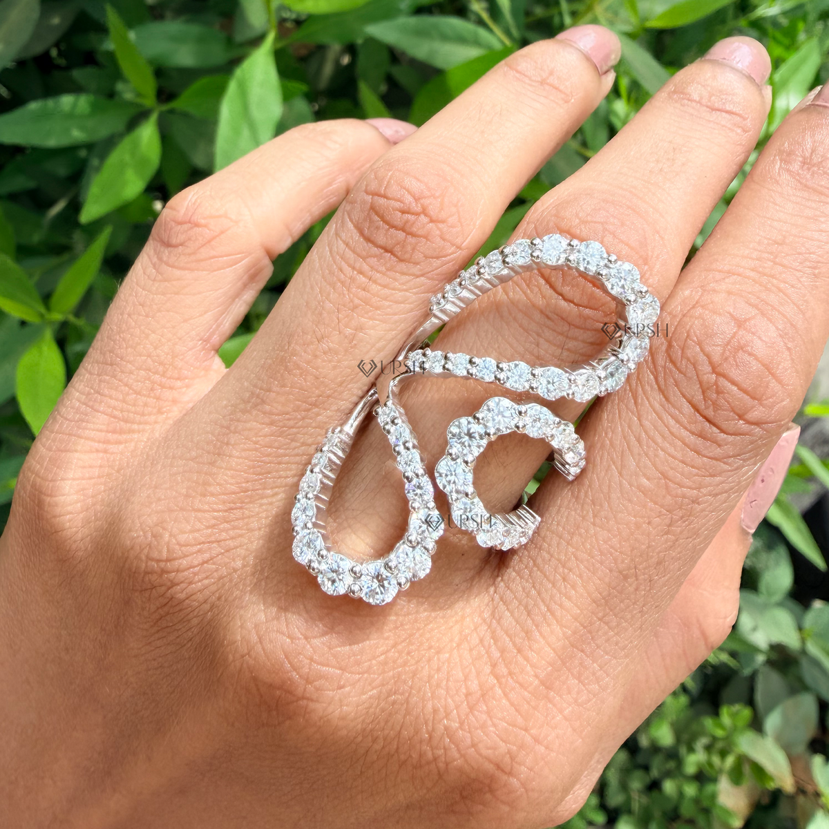 White gold multi-finger statement ring worn against natural garden greenery