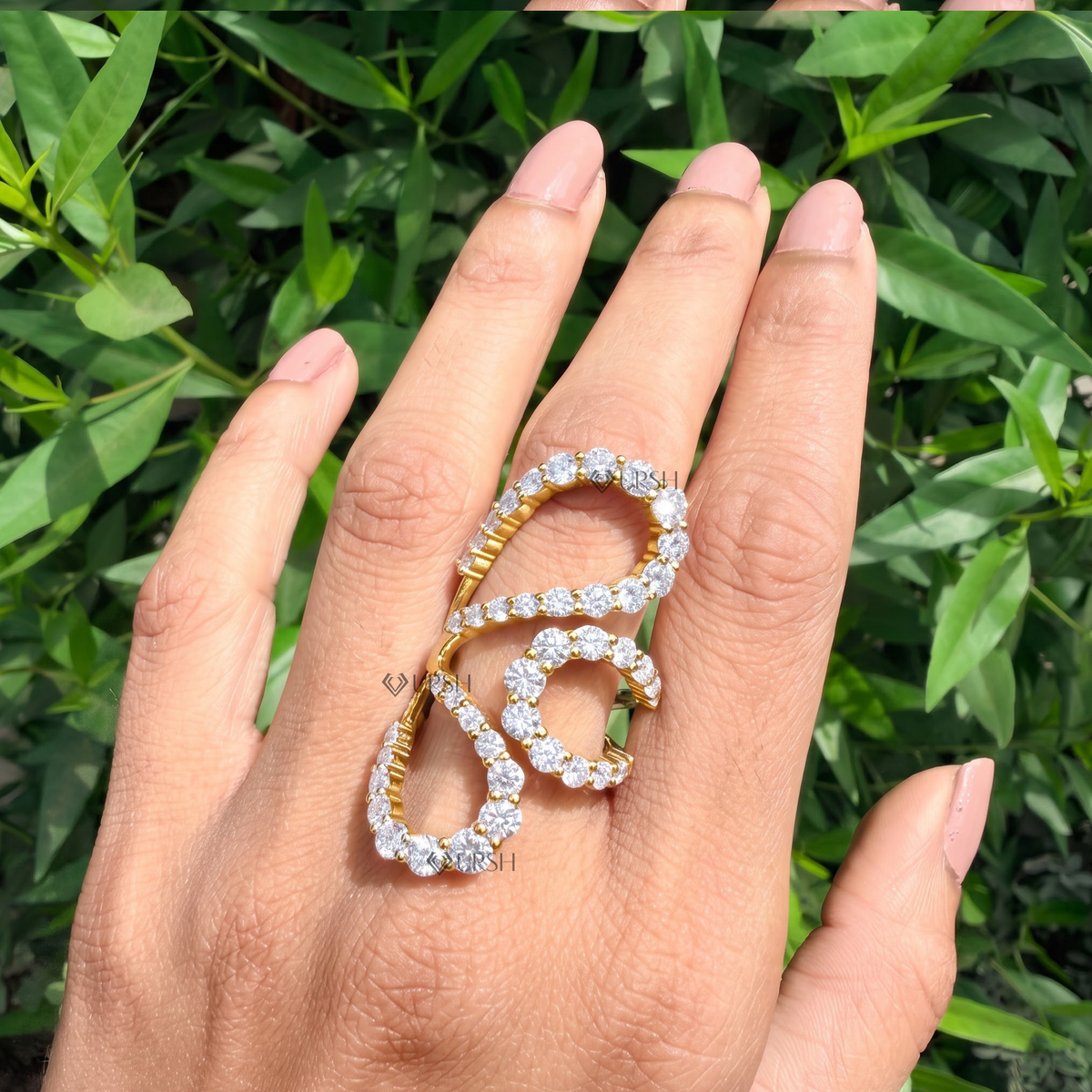 Detailed daylight macro close-up of interconnected micro-pavé loops on multi-finger statement ring worn on hand