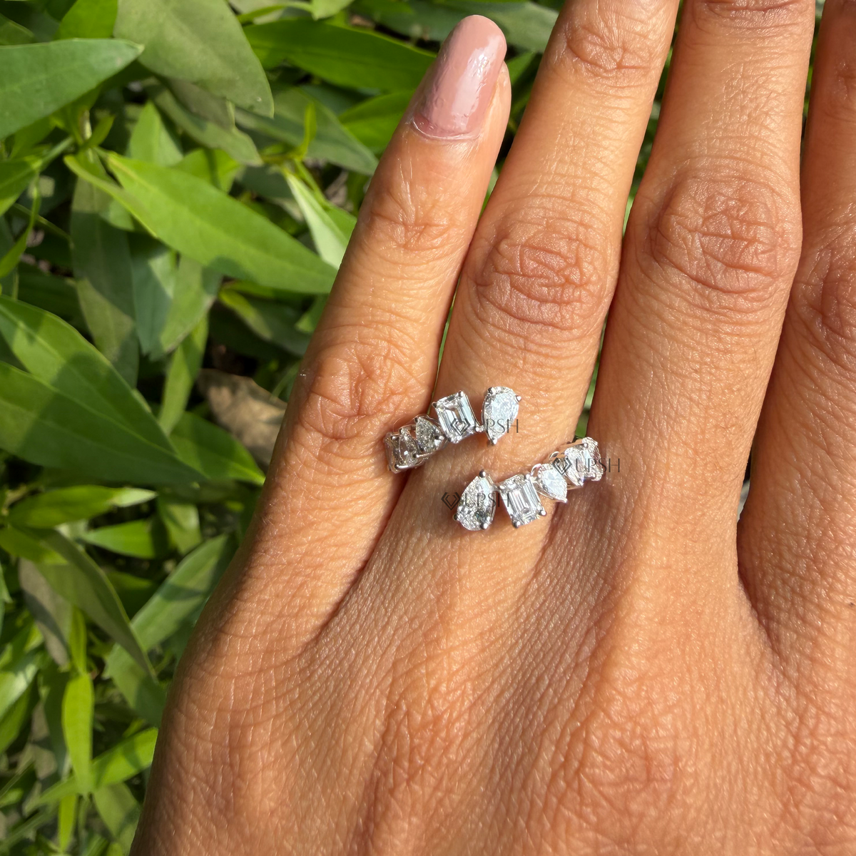 Daylight angle view of multi-shape diamond bypass ring worn against natural background