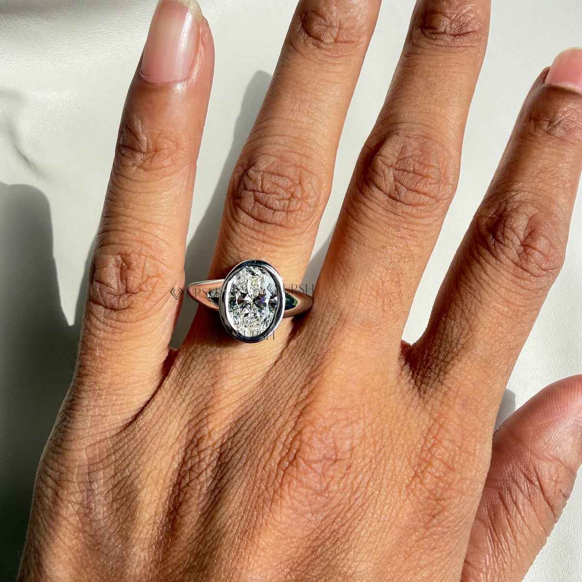 Yellow gold oval bezel solitaire ring worn against natural daylight