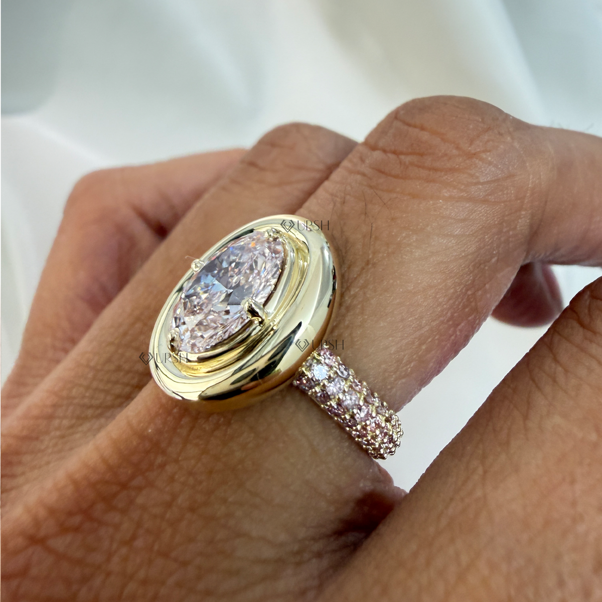 Detailed daylight macro close-up of oval light pink lab diamond in bold double-bezel setting worn on hand