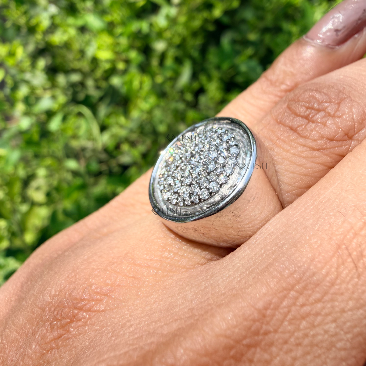 Daylight angle view of pavé disc signet ring worn on finger highlighting polished bezel frame