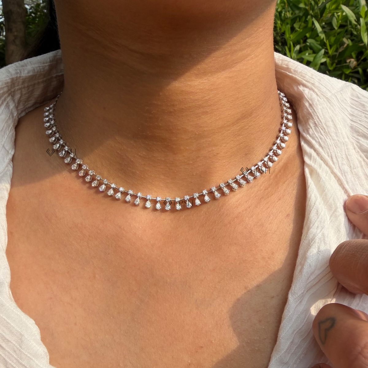 Daylight angle view of white gold cascading pear and round diamond dangle drop fringe necklace worn on neck