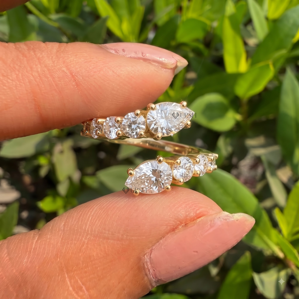 Detailed daylight macro close-up of pear and round cluster bypass ring showing prong settings and brilliant facet fire