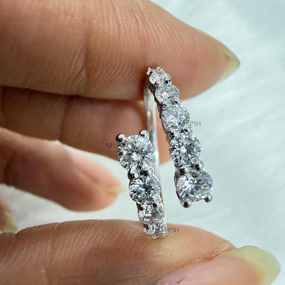 Close-up holding white gold shared-prong round diamond coil band showing open shank