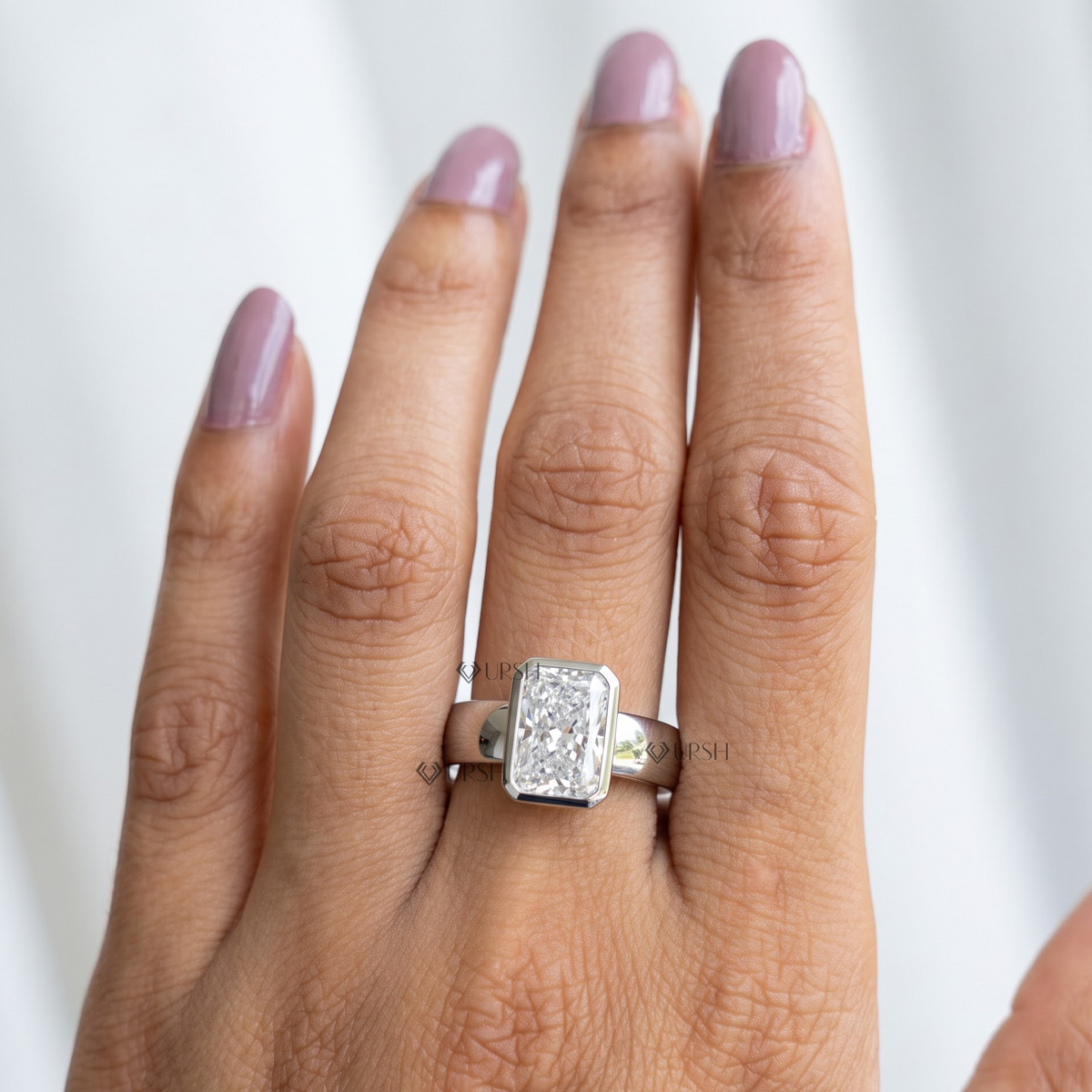 Radiant cut diamond bezel solitaire ring on hand in white gold
