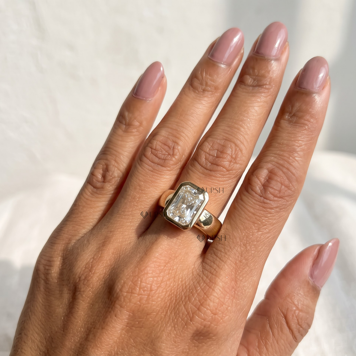 Full hand view of radiant cut diamond bezel ring in yellow gold on finger