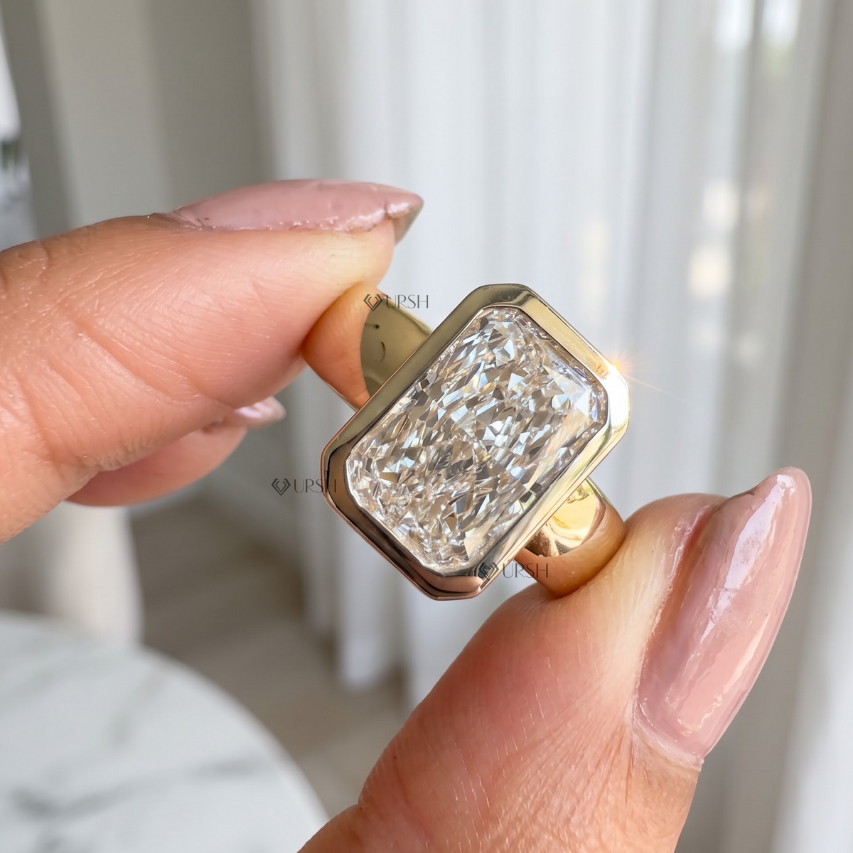 Detailed close up of yellow gold bezel setting holding elongated radiant cut diamond