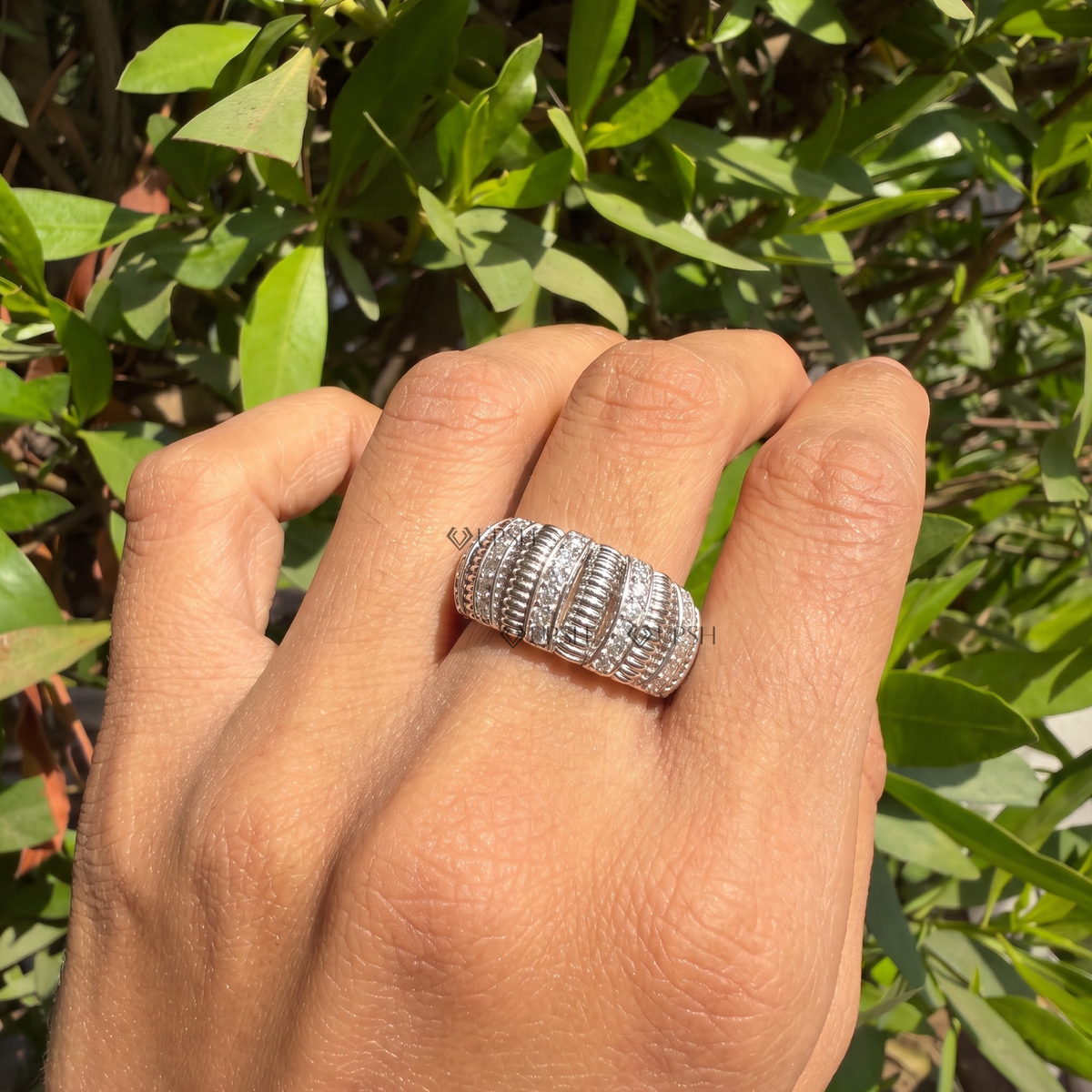 White gold ribbed cocktail ring worn against natural garden greenery