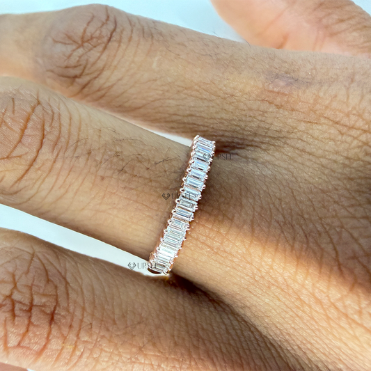Dainty baguette diamond stackable wedding band worn on ring finger against skin tone