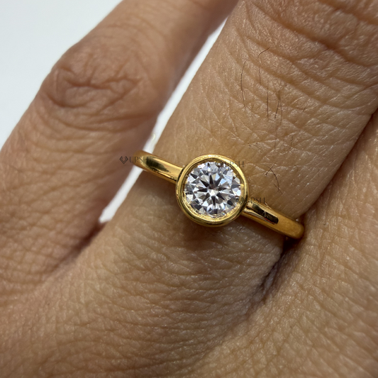 Detailed macro shot of brilliant round lab diamond encased in a polished solid yellow gold bezel frame
