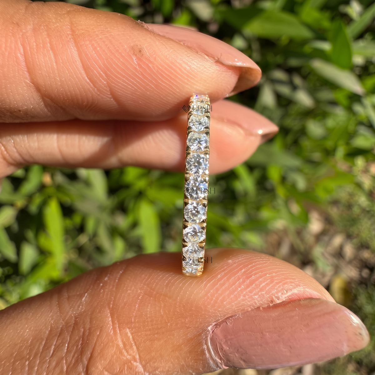 Detailed daylight macro close-up of shared-prong round lab diamonds held between fingertips