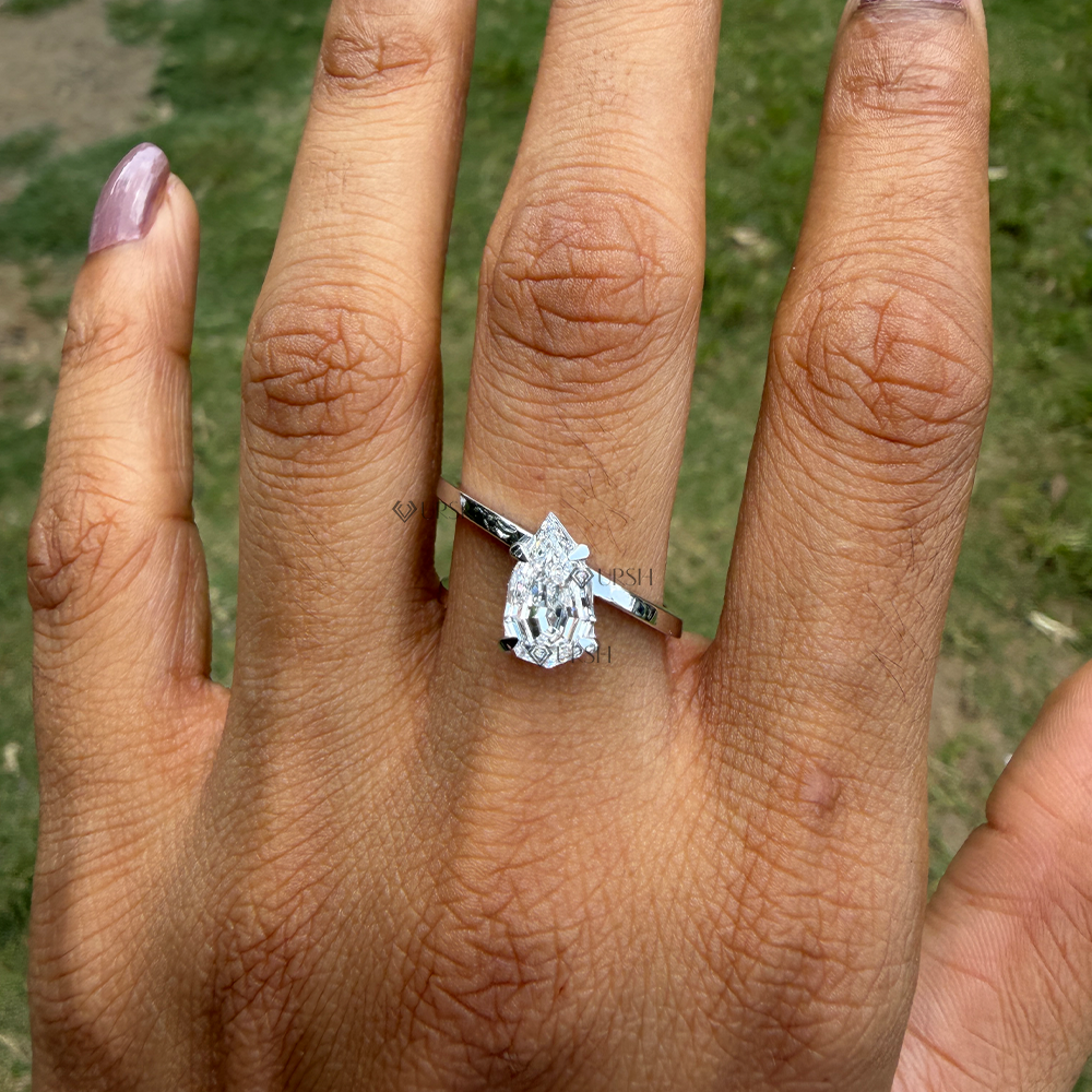 Minimalist white gold pear diamond bypass ring styled across finger in natural light