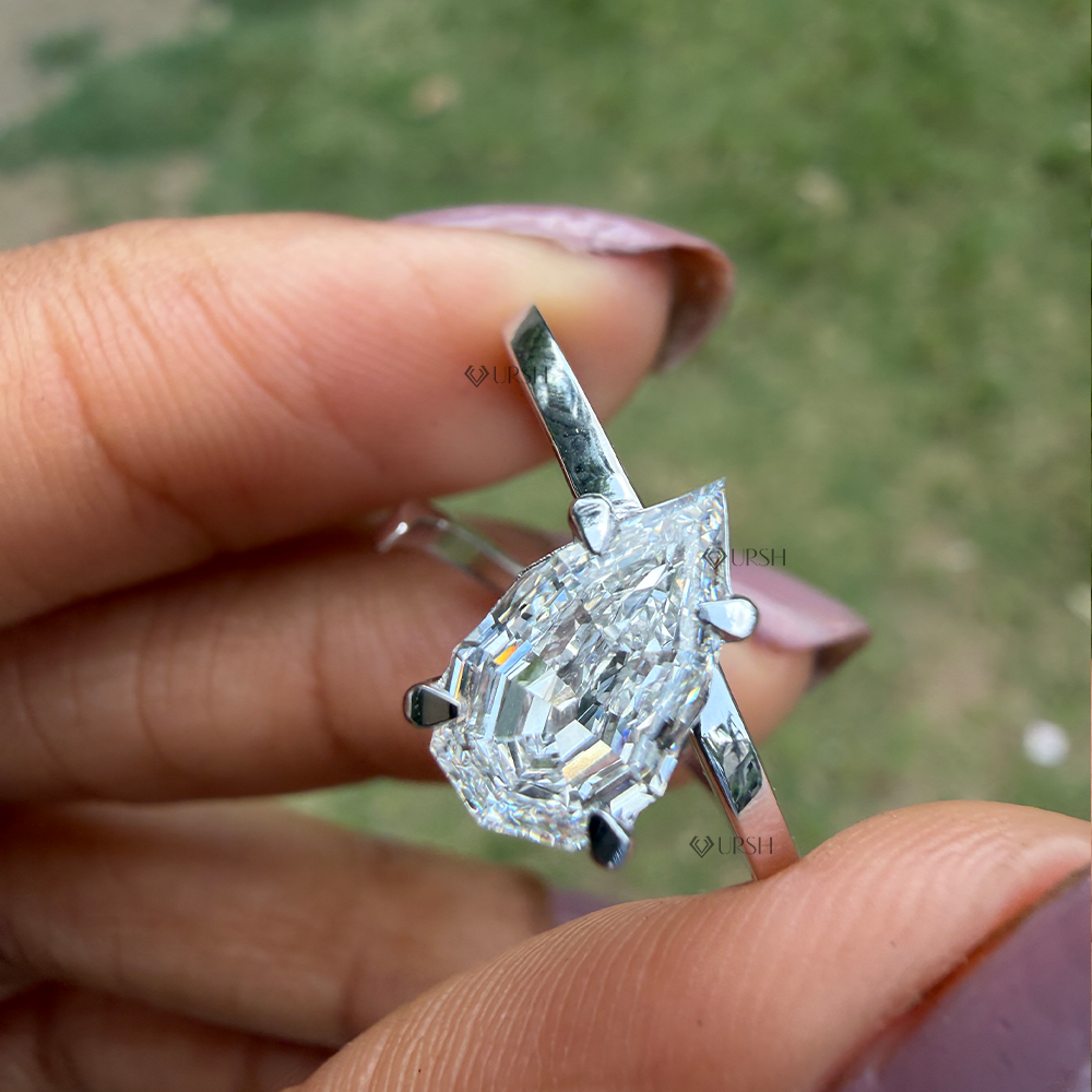 Close-up holding step cut pear diamond solitaire ring showing elevated bypass band structure