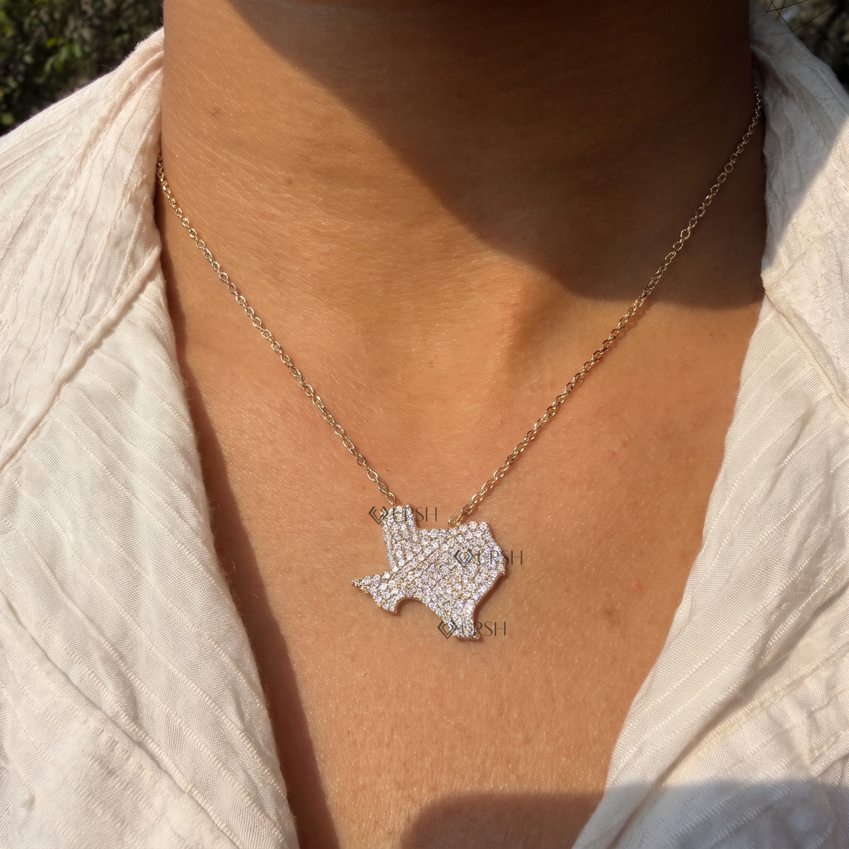Yellow gold Texas state map pavé diamond pendant necklace styled gracefully on neck in natural daylight