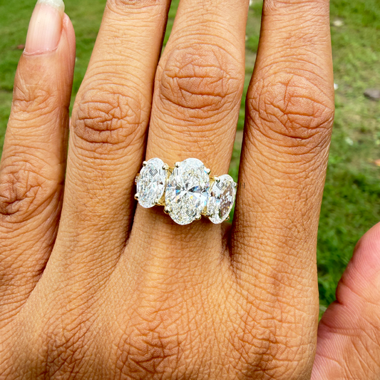 Detailed daylight close-up of three-stone oval lab diamond ring showing exceptional brilliance on hand
