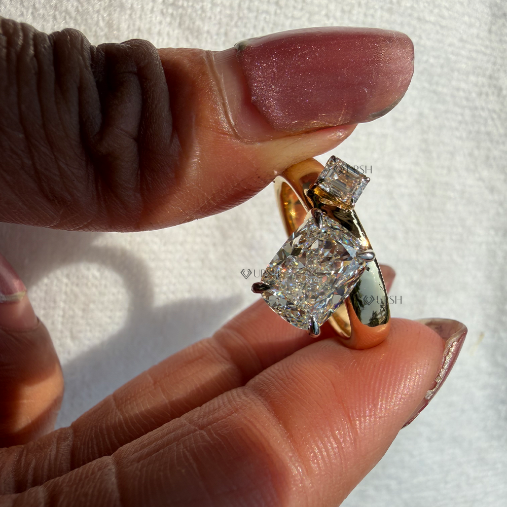 Side angle holding yellow gold cushion and emerald diamond ring showing elevated claw prong baskets