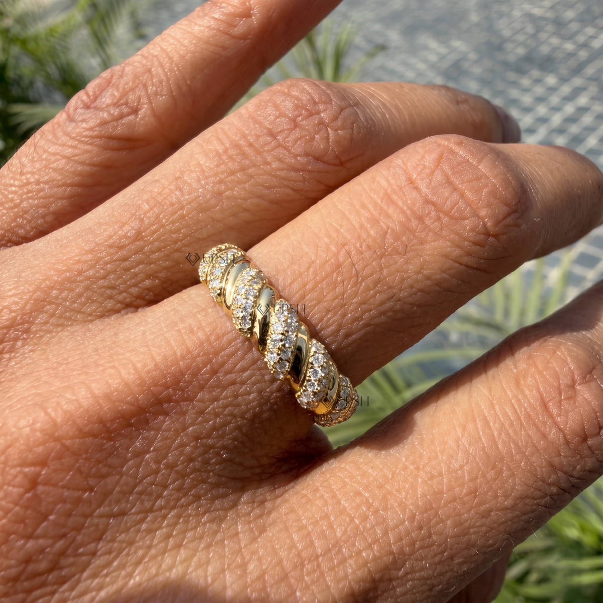 Close-up of yellow gold spiral ribbed band showing diamond brilliance against warm skin tones