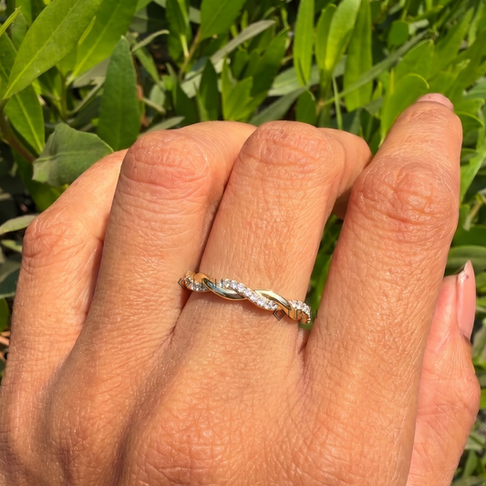 Twisted yellow gold wedding band styled gracefully on finger in natural daylight