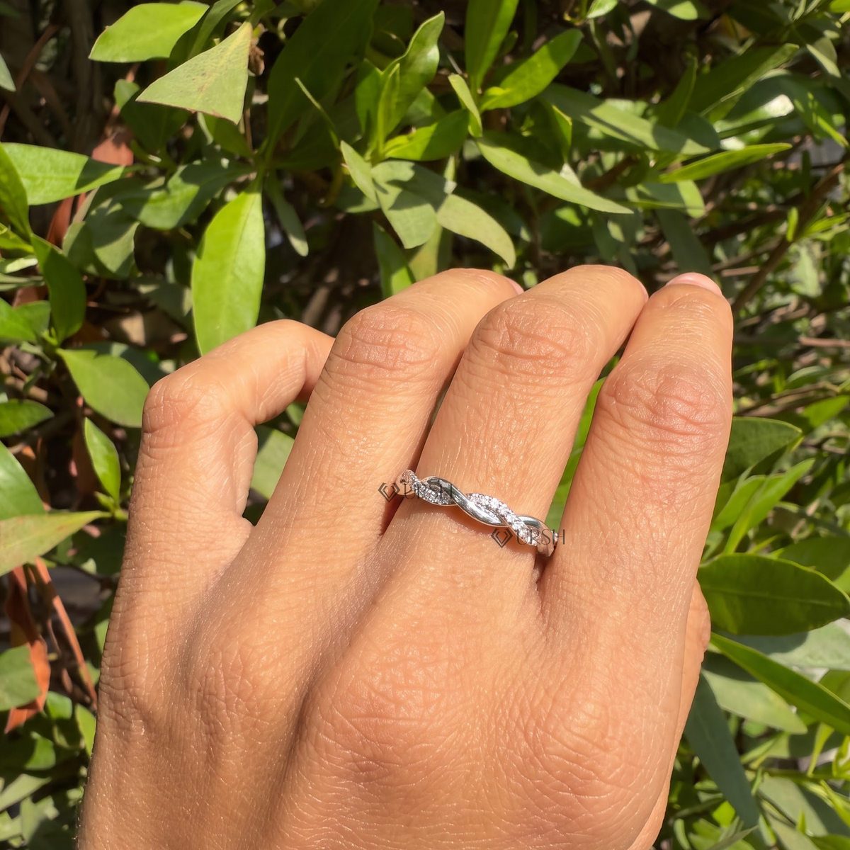 White gold twisted rope stackable ring worn against natural garden greenery