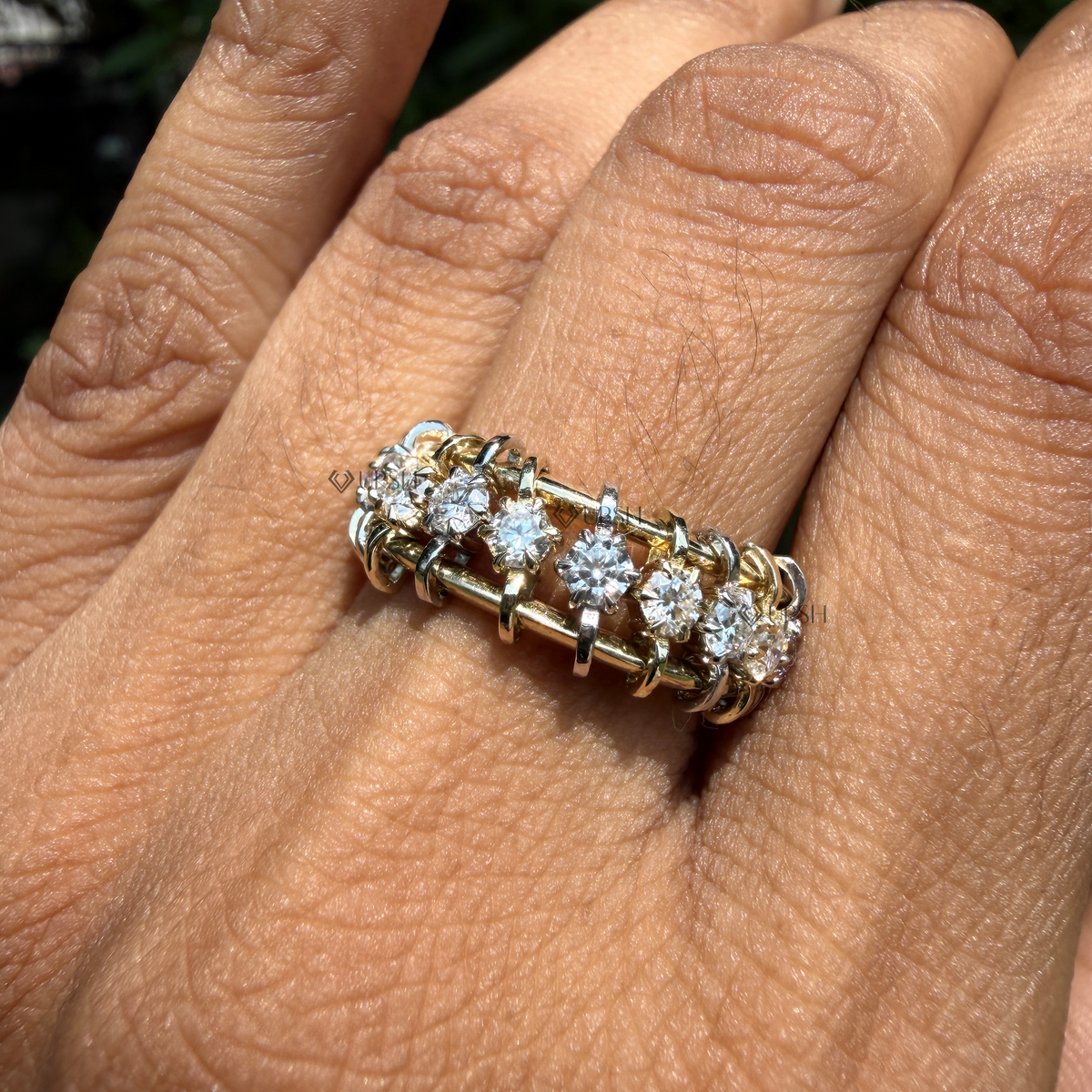 Close-up top-down view of a two-tone diamond band ring worn on a finger.