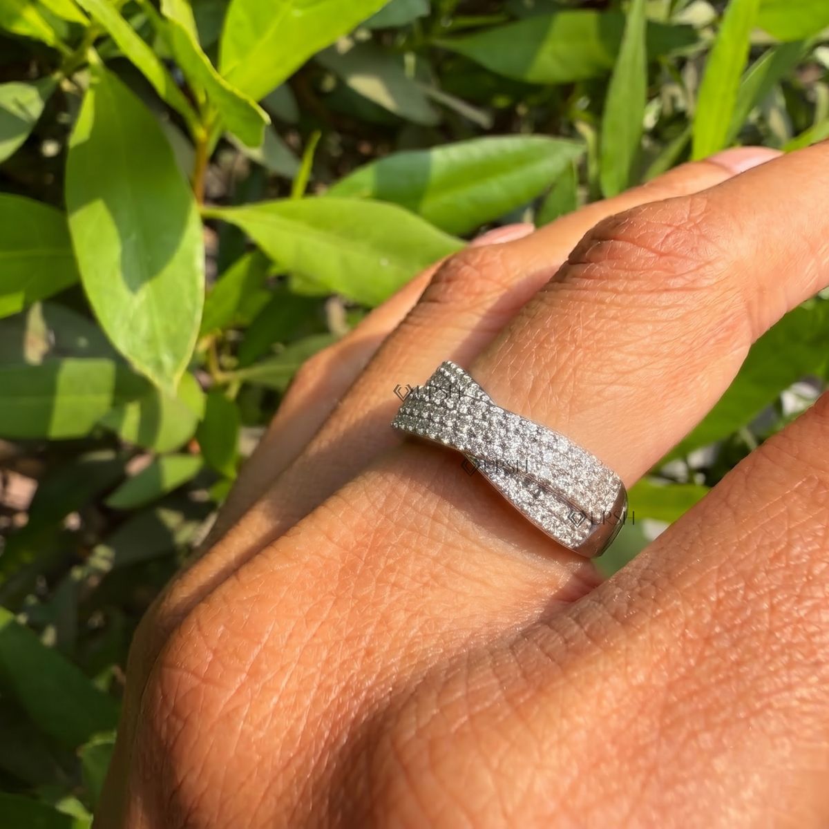 Detailed daylight angle view of wide multi-row cross pavé ring worn on finger