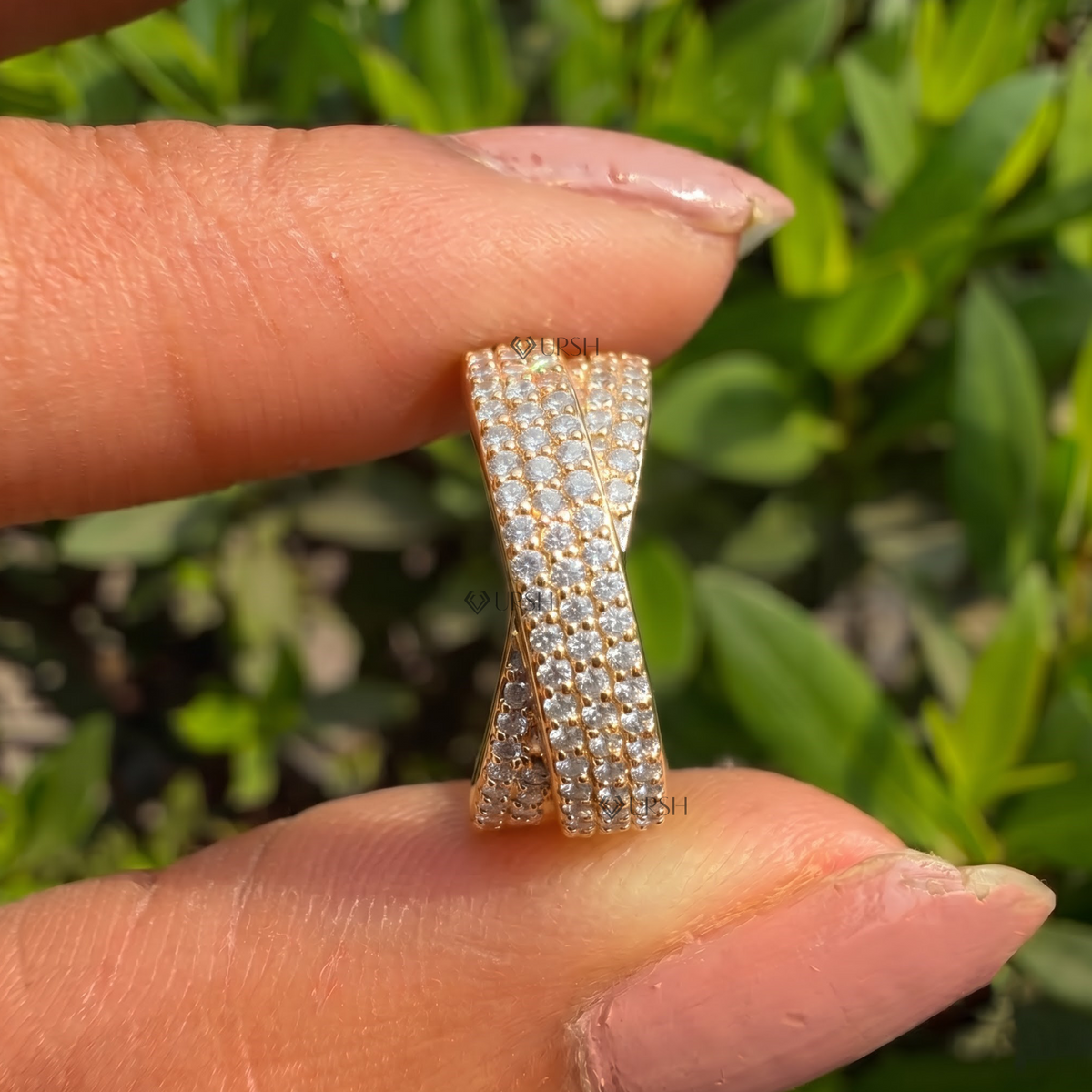 Holding solid yellow gold wide criss-cross band showcasing side profile and dense pavé thickness