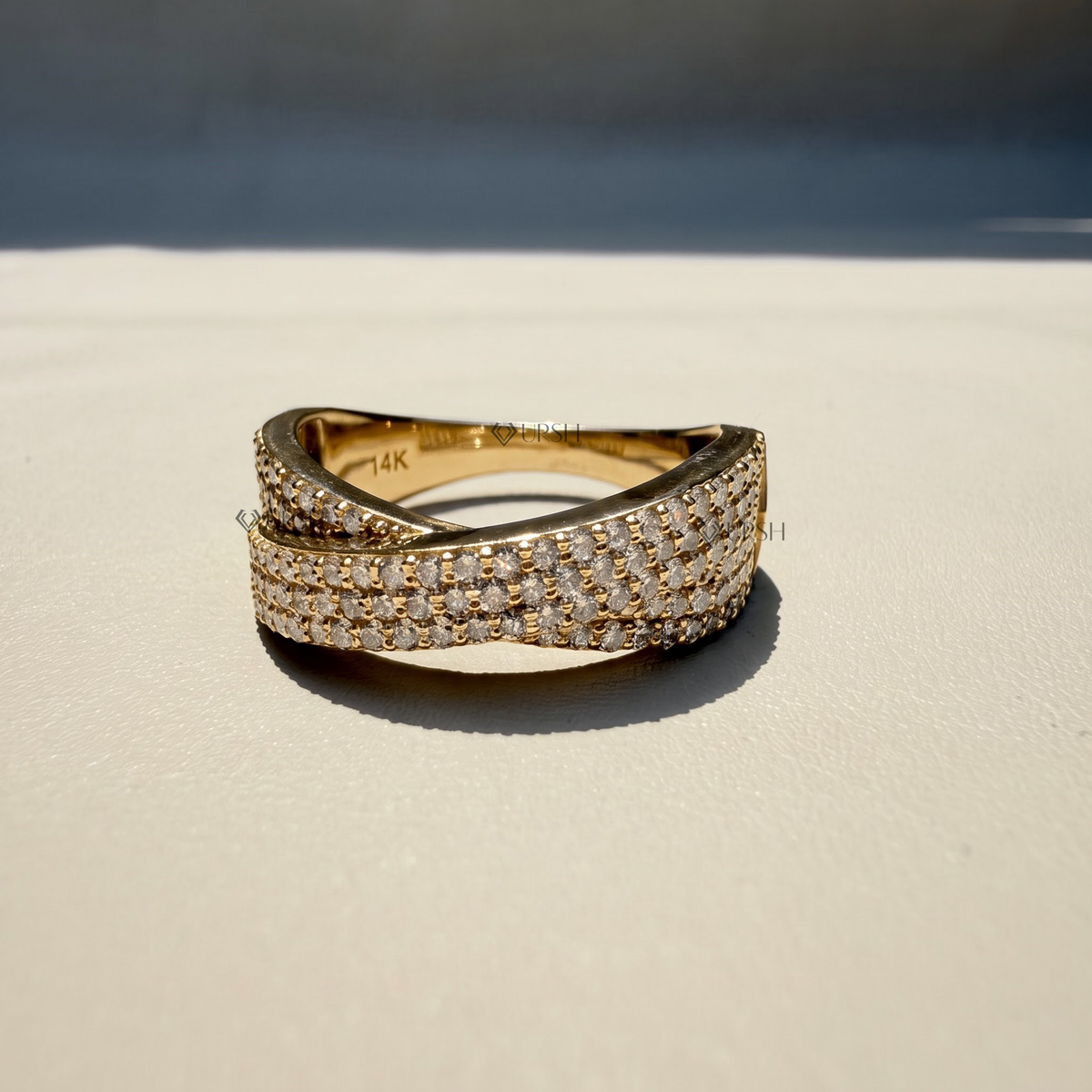 Studio view of yellow gold wide crossing band displaying interlaced profile and polished finish