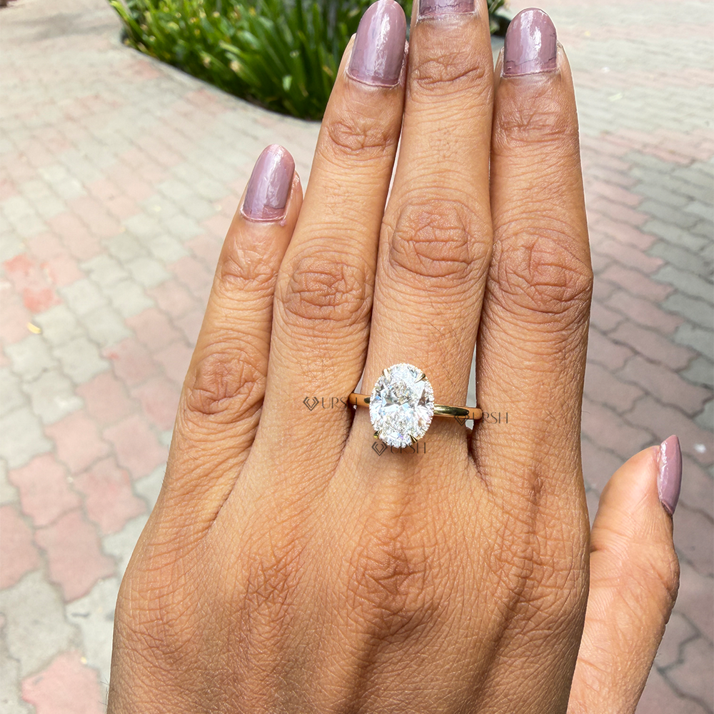 Delicate thin solid gold band oval diamond solitaire ring on ring finger