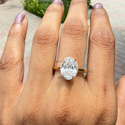 Oval cut lab diamond hidden halo engagement ring worn on hand outdoors