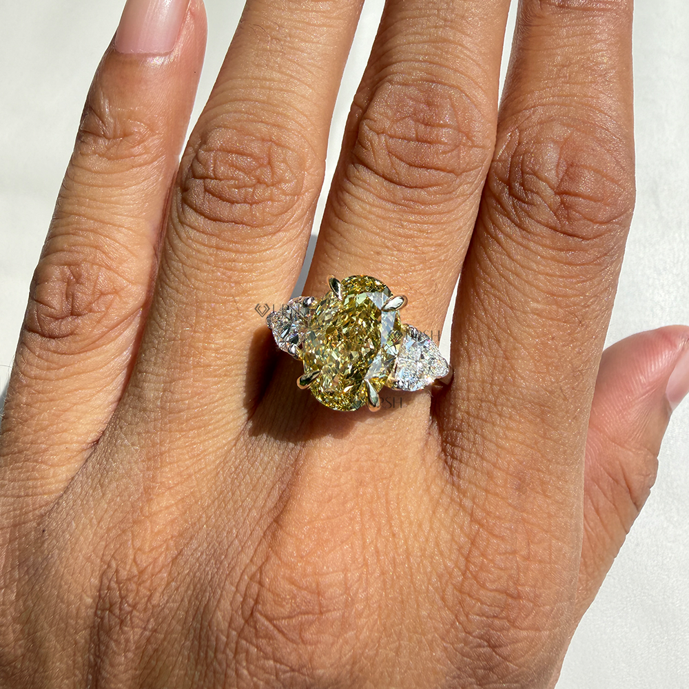 Stunning yellow oval diamond trilogy ring styled gracefully on hand in natural light