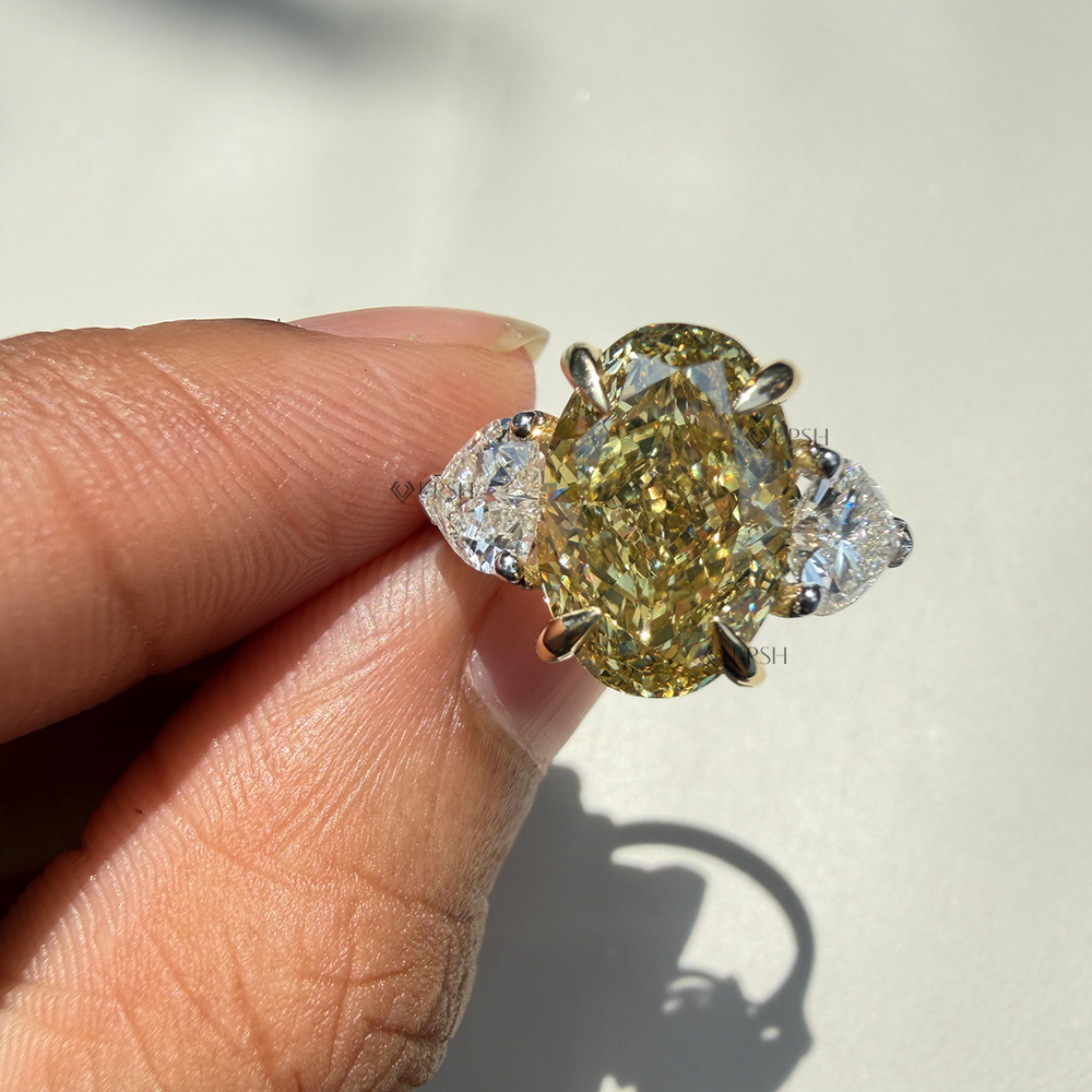Holding two-tone yellow diamond ring showcasing raised prongs and side pear stone brilliance