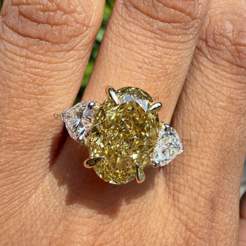 Detailed daylight macro view of canary yellow oval lab diamond and colorless pear side stones on hand