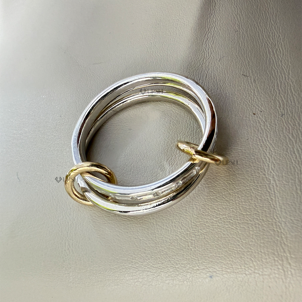 Studio close-up perspective of two-tone interlocking baguette diamond ring showing linked silver and gold bands on a neutral surface