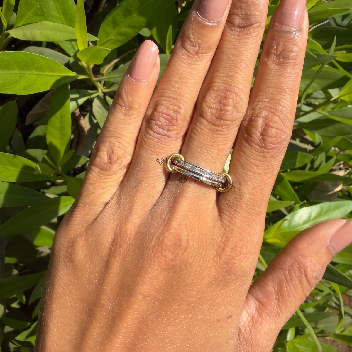 Interlocking multi-band baguette ring worn against natural garden greenery showcasing horizontal finger presence