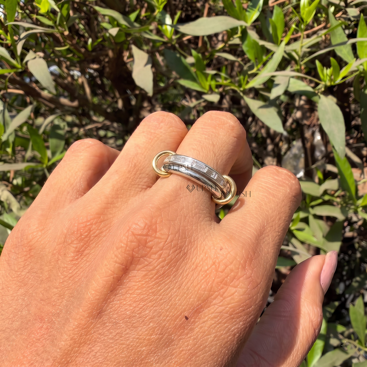 Two-tone interlocking baguette diamond ring styled gracefully on finger in natural daylight