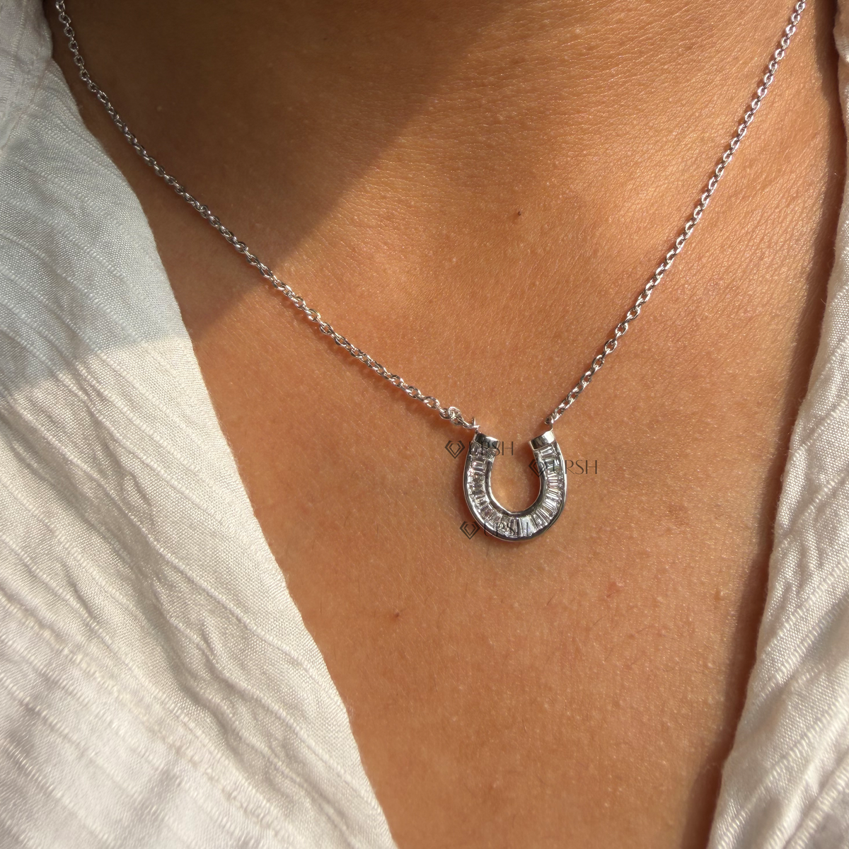 Daylight perspective view of white gold lucky horseshoe diamond pendant worn on collarbone