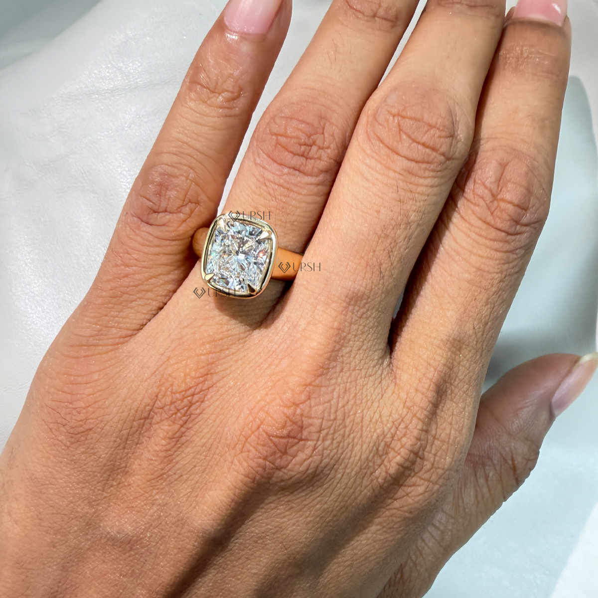 On-hand view of bold cushion diamond puffy bezel engagement ring with wide gold band