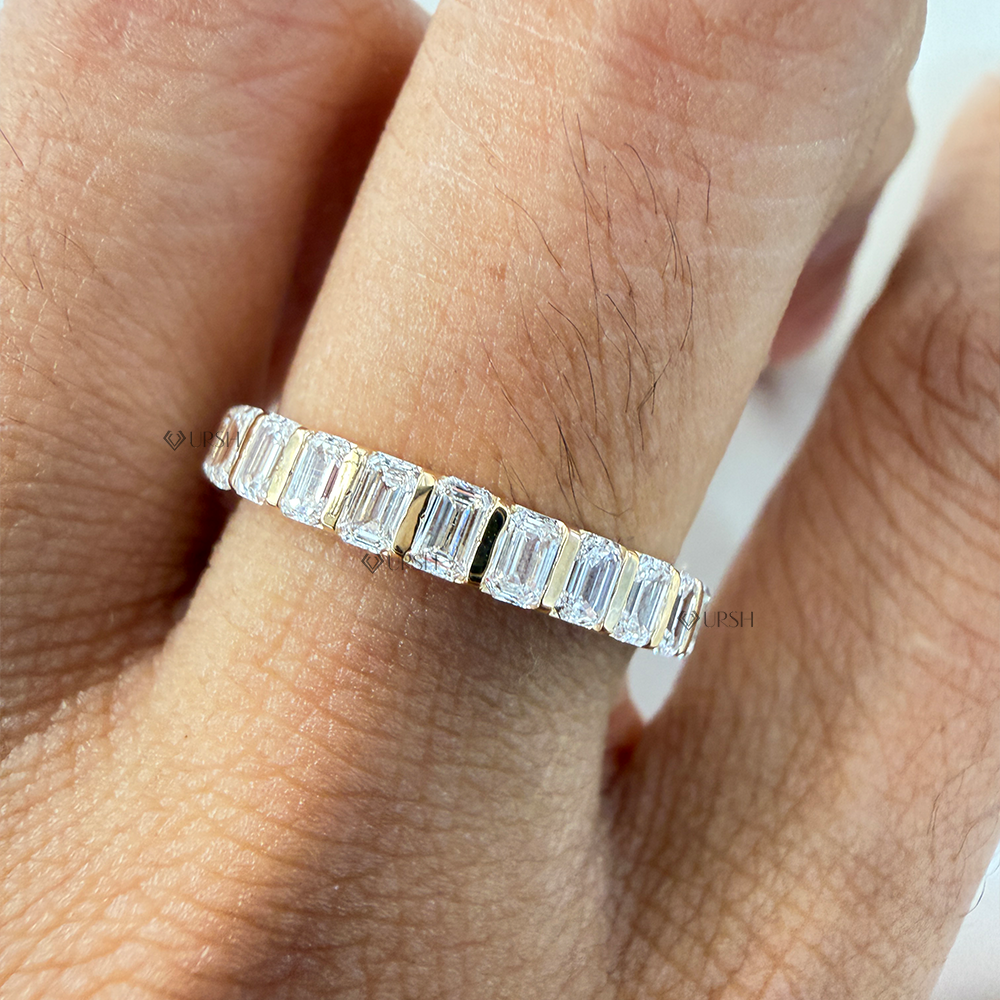 Finger perspective showing clean step-cut diamond flash across emerald cut gold band
