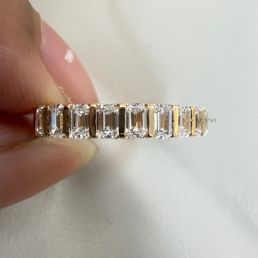 Close-up holding solid gold bar set emerald diamond band highlighting polished metal bars