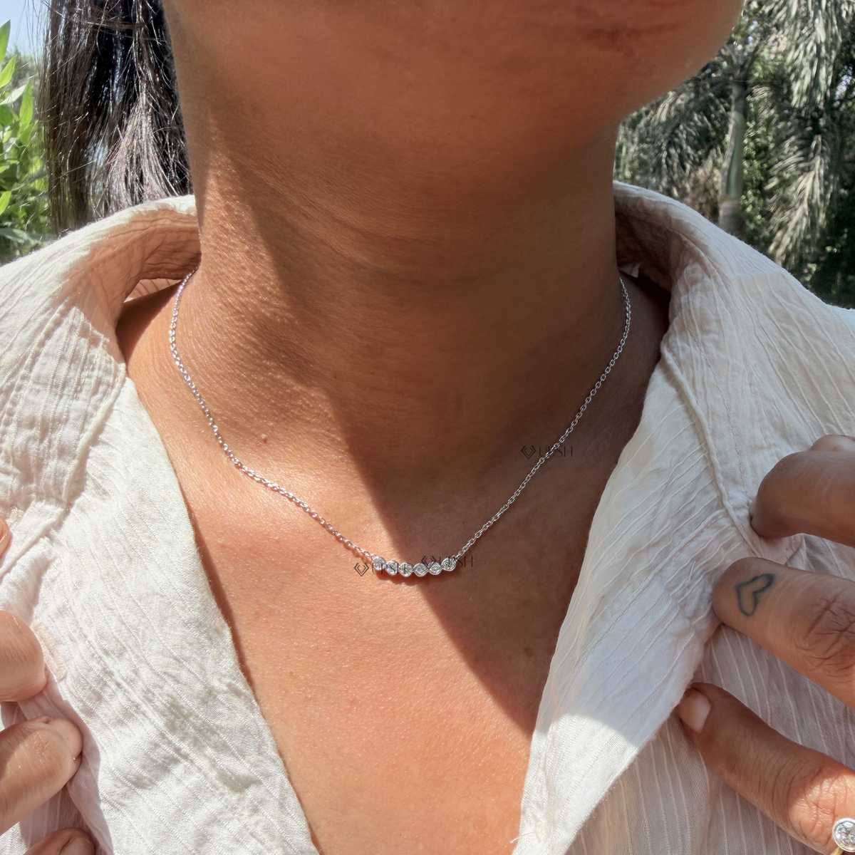Daylight angle view of white gold curved bezel diamond smile bar pendant chain worn on neck