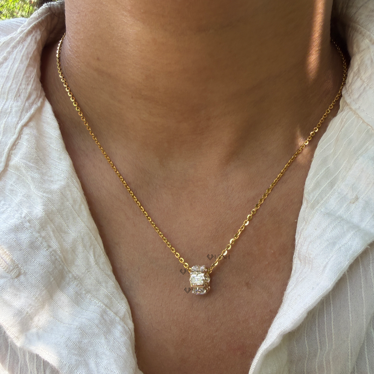 Daylight perspective of yellow gold emerald cut diamond rondelle charm pendant worn along collarbone