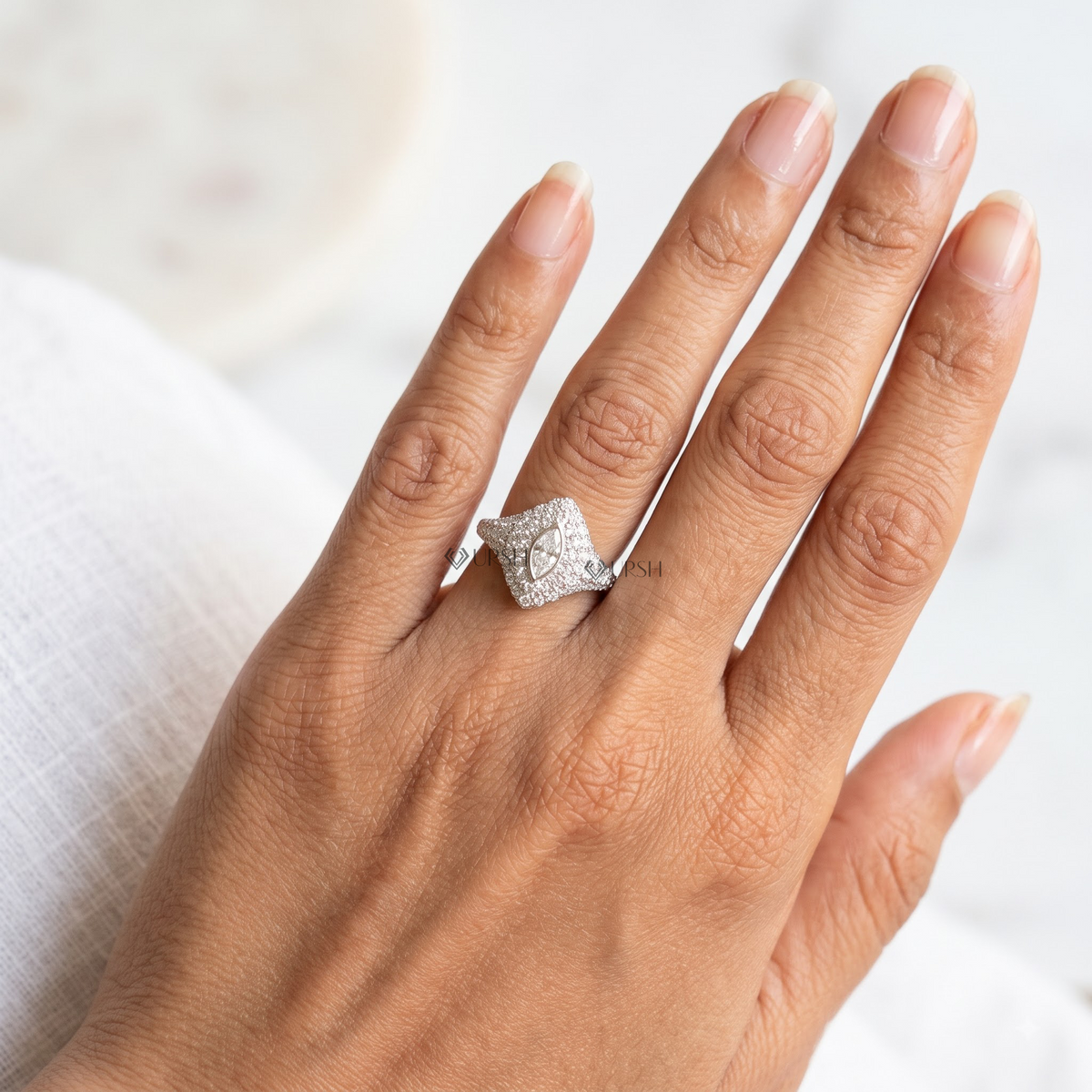 Lab grown marquise diamond signet statement ring in white gold worn on woman's ring finger.